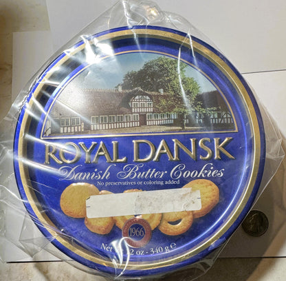 Royal Dansk Danish Butter Cookies tin with blue and gold trim, half-wrapped in plastic, shown with penny for scale.