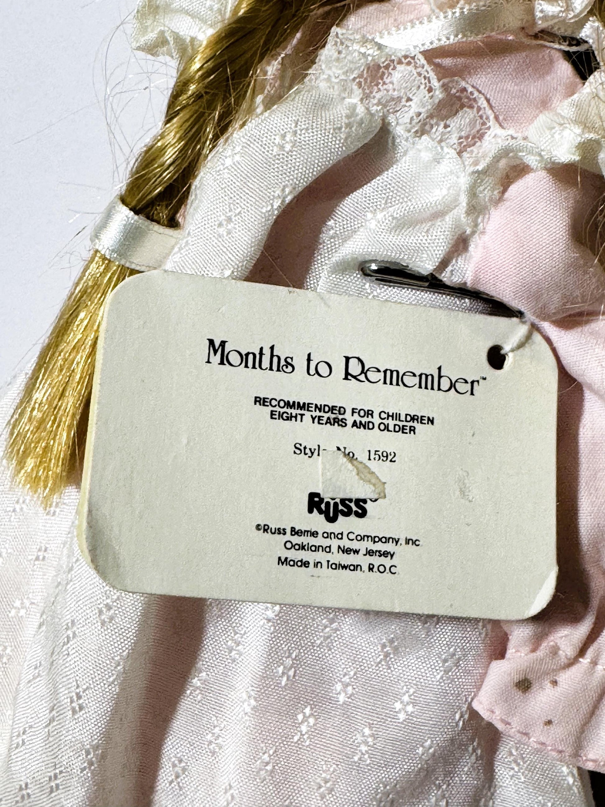 Close-up of product tag attached to vintage doll reading "Months to Remember" and "Russ" with style number 1592, made in Taiw