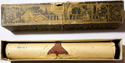 Ornate player piano roll box with classical engraved lid showing reclining figures in garden, containing cream-colored paper 
