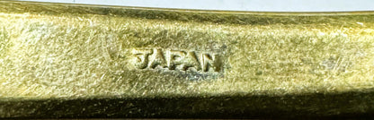 Close-up of embossed "JAPAN" marking on textured gold-tone brass flatware handle