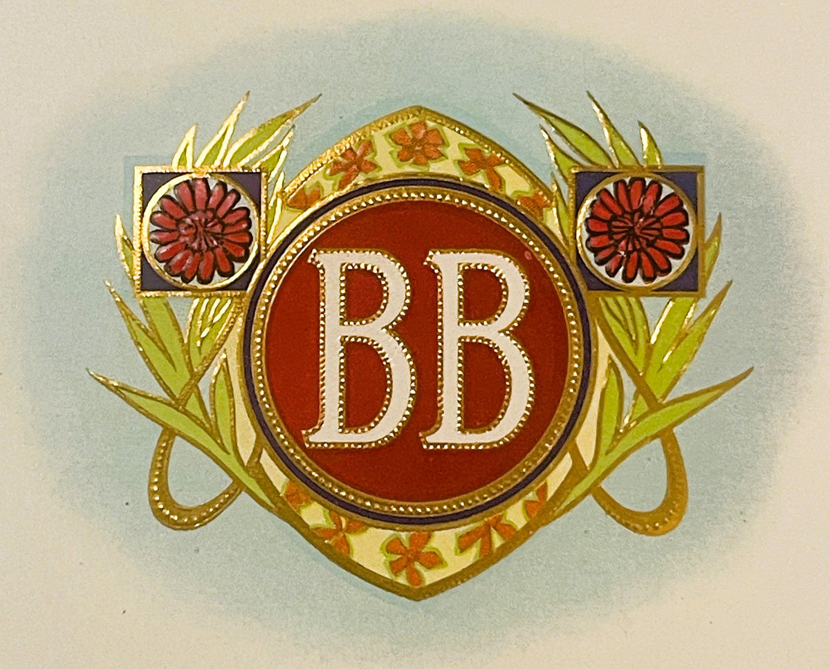Antique gold-embossed cigar label close-up: white BB monogram on a red medallion in a gold frame, red flowers in purple squares on each side, green leaves, on a pale blue haze.