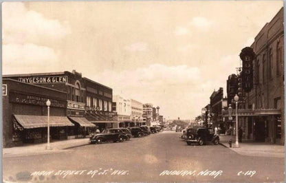 Sepia-toned street view of Auburn, Nebraska showing Main Street with Thygeson & Glen drugstore and period automobiles from ap