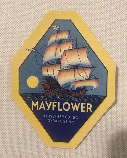 Hexagonal yellow and blue vintage broom label featuring a sailing ship with tan sails, moon, and text reading "MAYFLOWER"