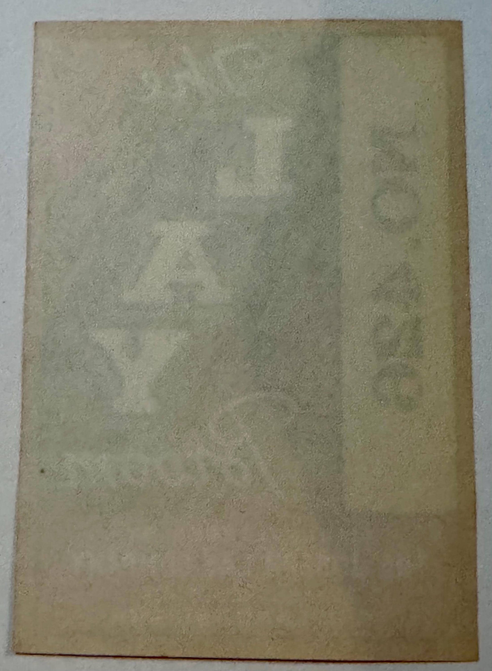 Faded aged paper label showing ghost impressions of text through the reverse side.