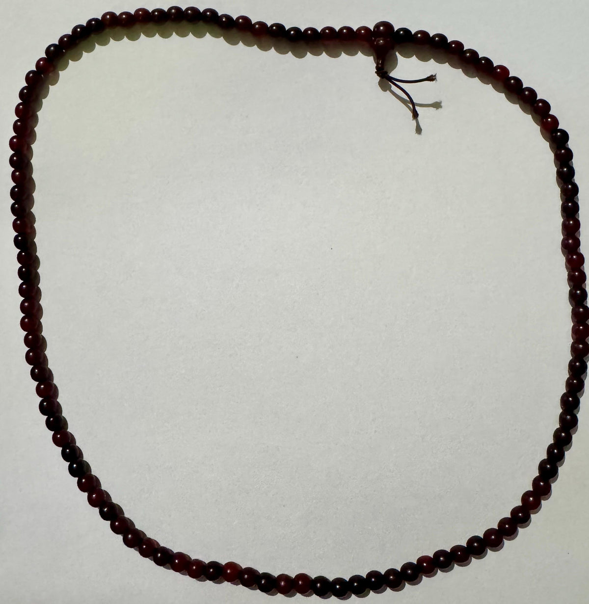 The full horn bead strand opened into one loop on white, the head bead and tied cord tails at the top