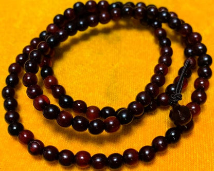 Close-up of the horn beads coiled on a yellow cushion, showing the bead grain and the gourd-shaped head bead tied off with a decorative knot