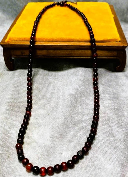 The 26-inch horn bead necklace draped over a small wooden stand, hanging as a single strand