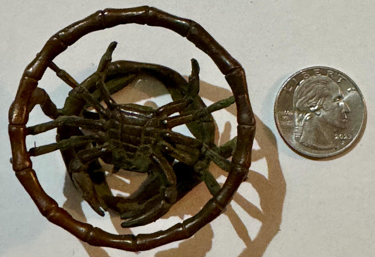 Bronze crab figurine with segmented bamboo-style ring handle, shown with quarter for scale.