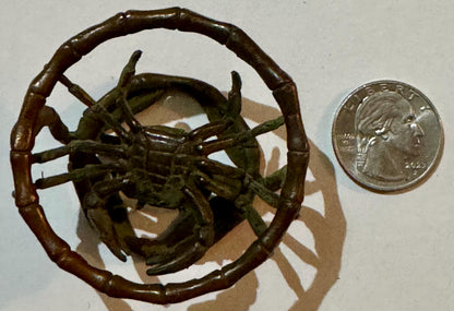 Bronze crab figurine with segmented bamboo-style ring handle, shown with quarter for scale.