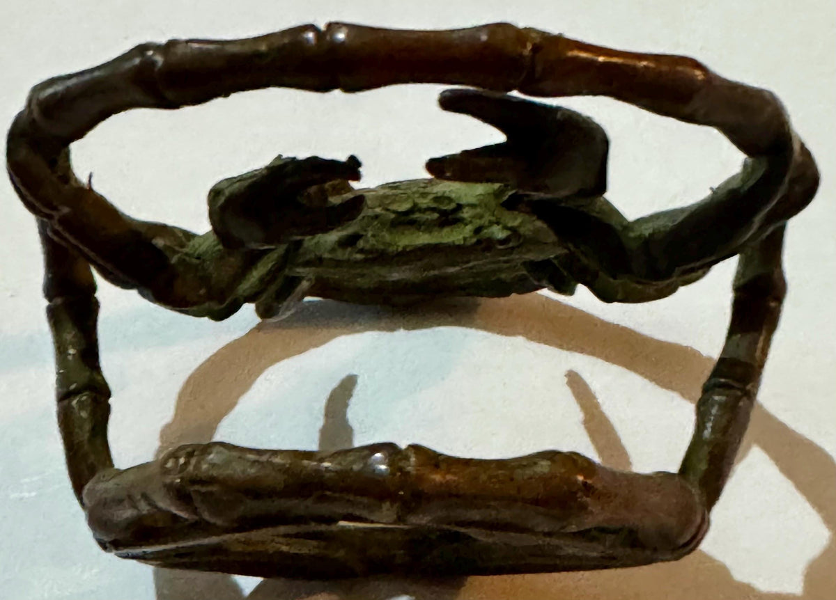 Bronze crab ornament with patina, bamboo-style ring frame, front view.
