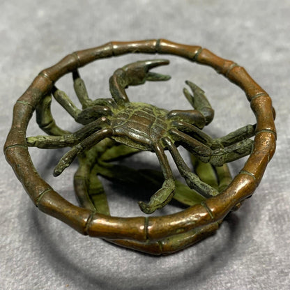 Bronze crab figurine with extended claws set within a bamboo-textured ring frame.