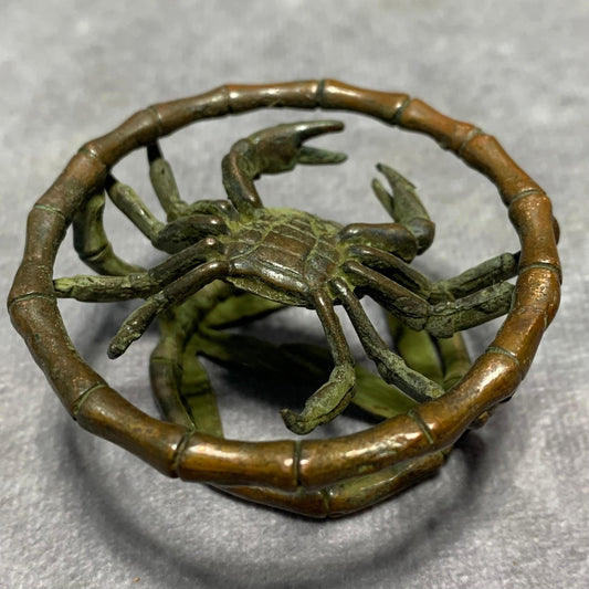 Bronze crab figurine with extended claws set within a bamboo-textured ring frame.