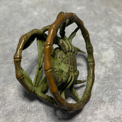 Vintage bronze crab ornament with green patina seated in bamboo ring.