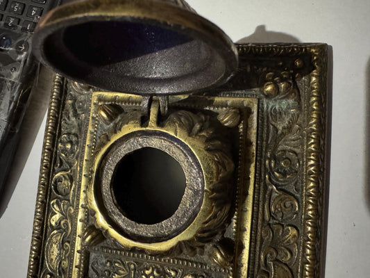 Open lid on the brass double inkstand revealing the bare, unlined well interior, close-up