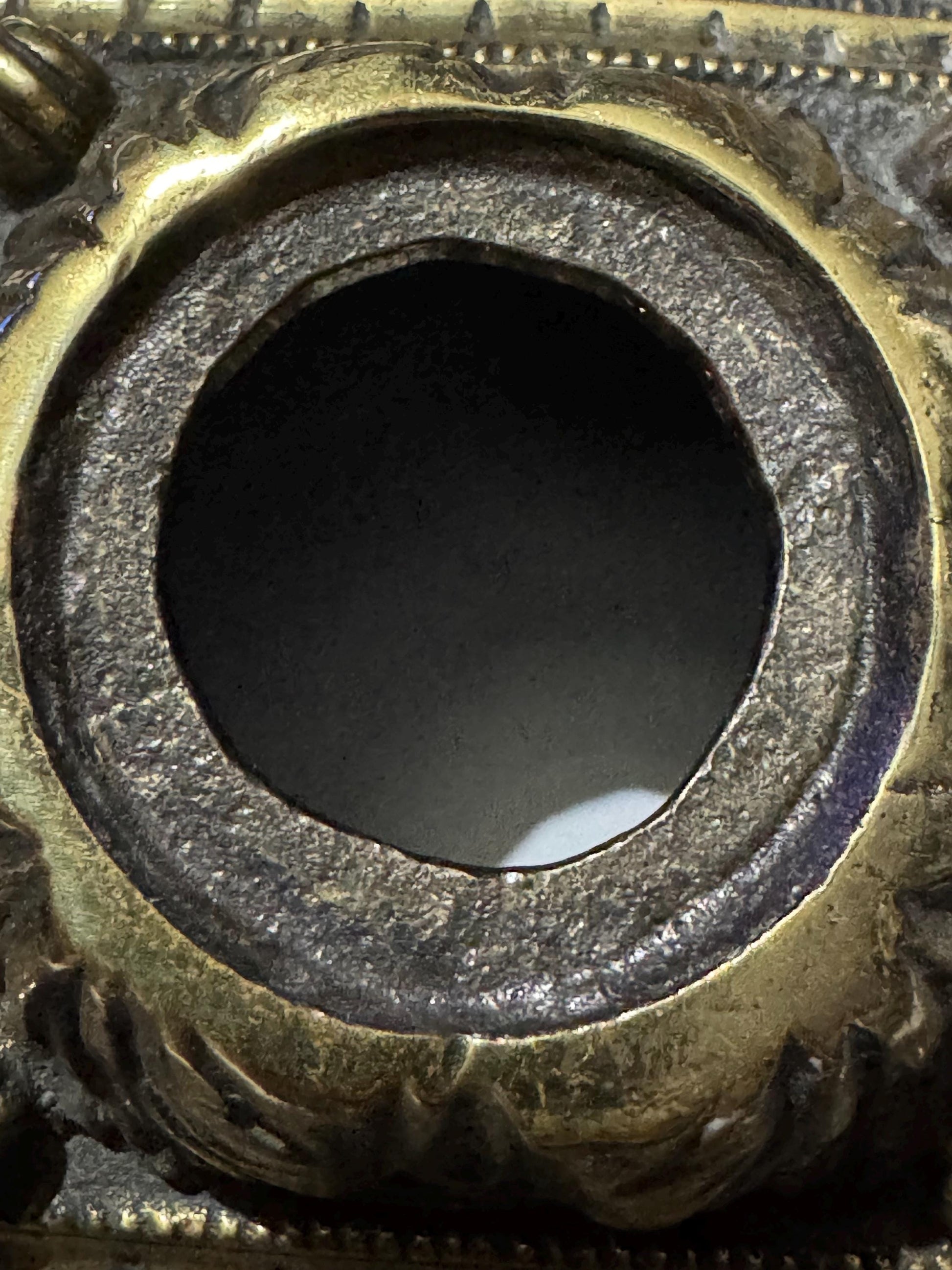 Macro close-up straight down into the second bare, unlined brass well