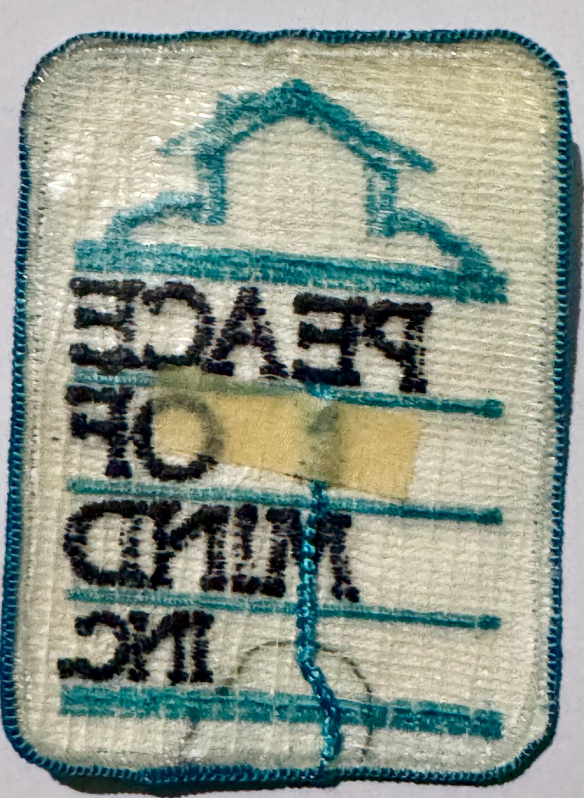 Back of the Peace of Mind Inc. patch showing the house, cloud and lettering stitched in reverse