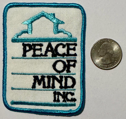 Peace of Mind Inc. patch next to a quarter for size, 3 1/4 by 2 1/2 inches