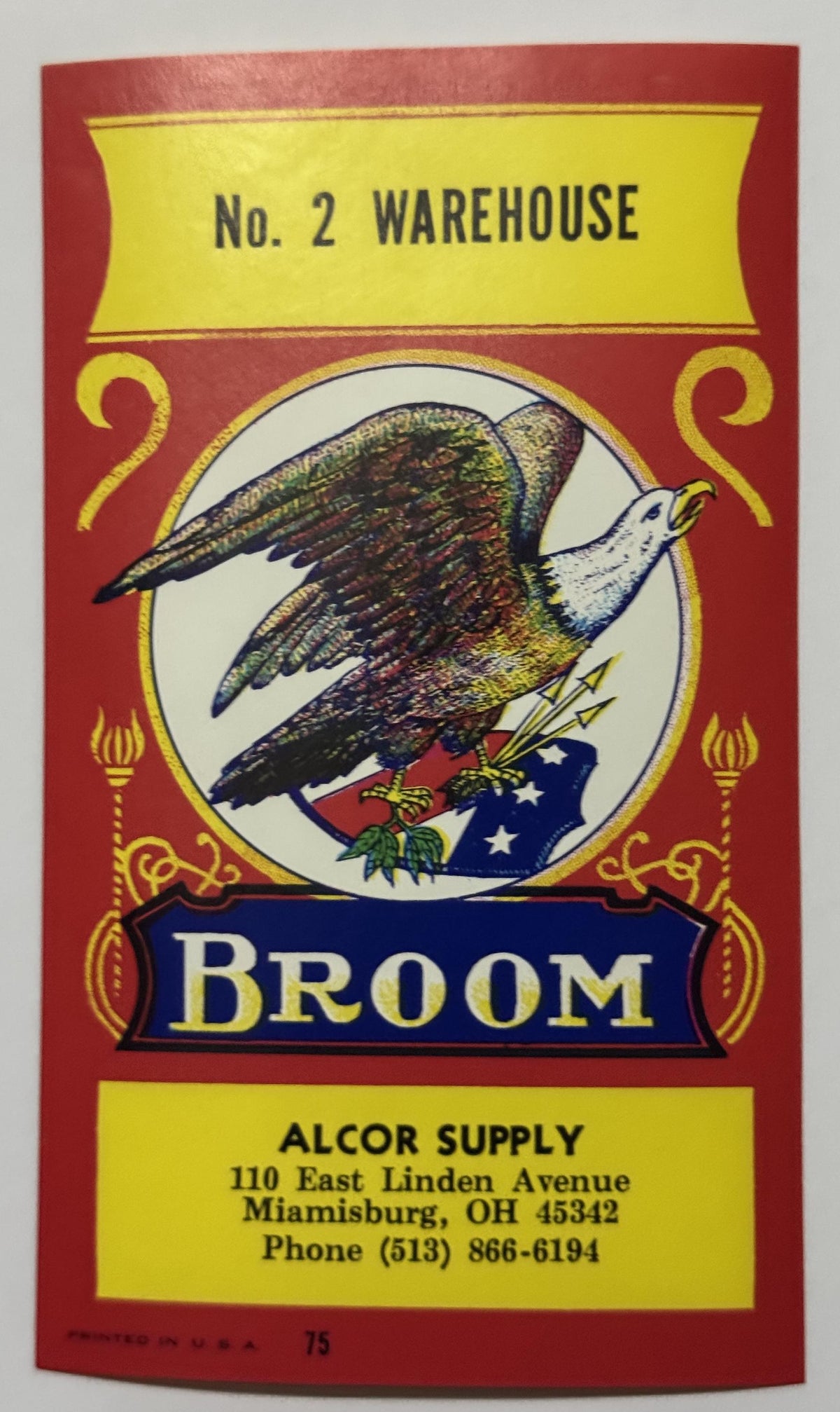 Alcor Supply No. 2 Warehouse broom label: a bald eagle on a starred flag with arrows and olive leaves in a white roundel, BROOM on a royal-blue banner, red field with yellow panels