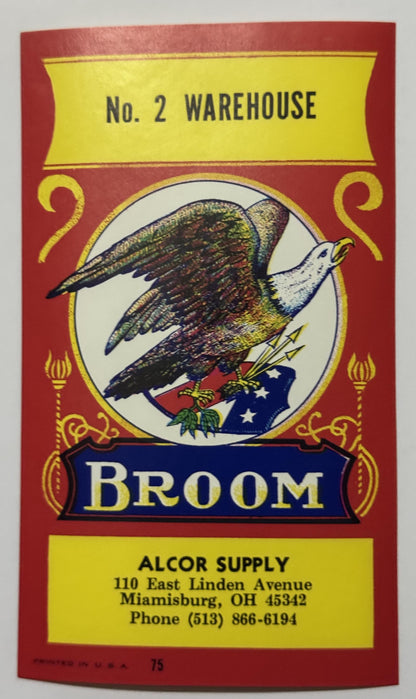 Alcor Supply No. 2 Warehouse broom label: a bald eagle on a starred flag with arrows and olive leaves in a white roundel, BROOM on a royal-blue banner, red field with yellow panels