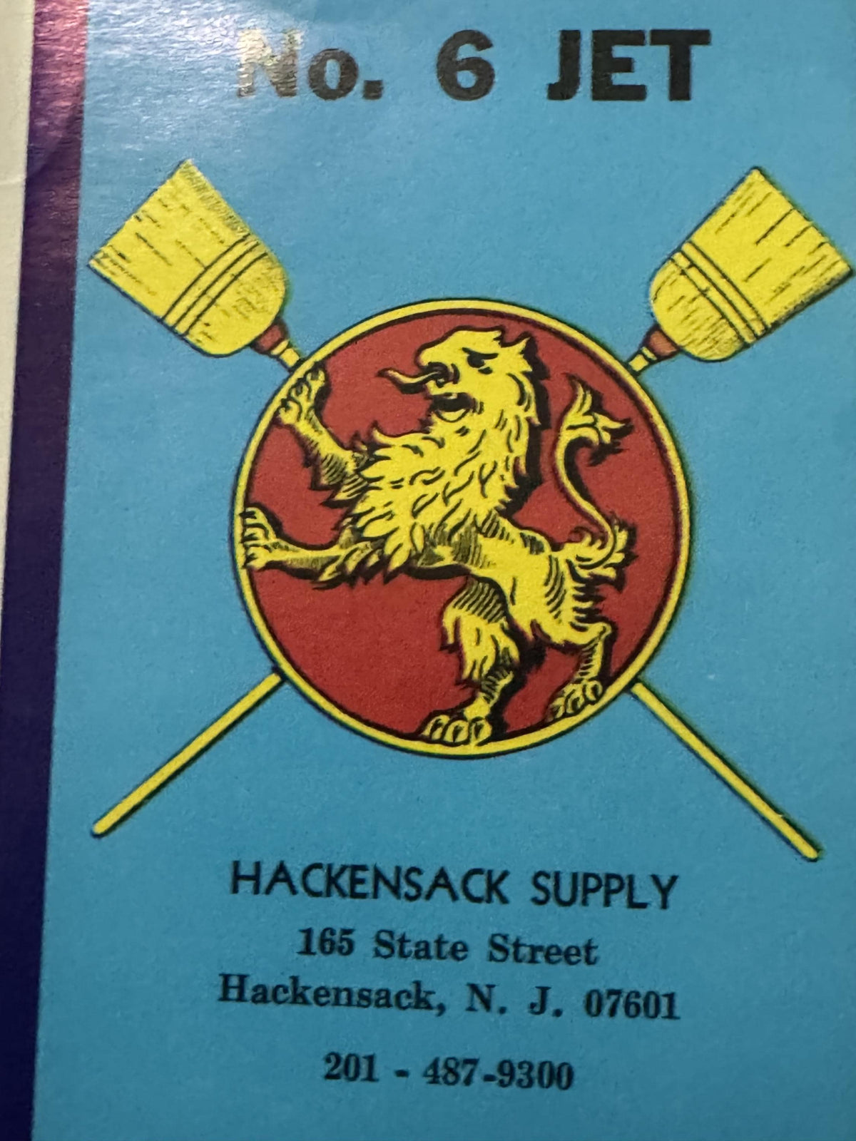 Upper part of the label: No. 6 JET in black above the crossed brooms and the lion on its red disc, the Hackensack Supply imprint below