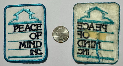 Front and back of the Peace of Mind Inc. patch beside a quarter for scale, the back showing the embroidery in reverse