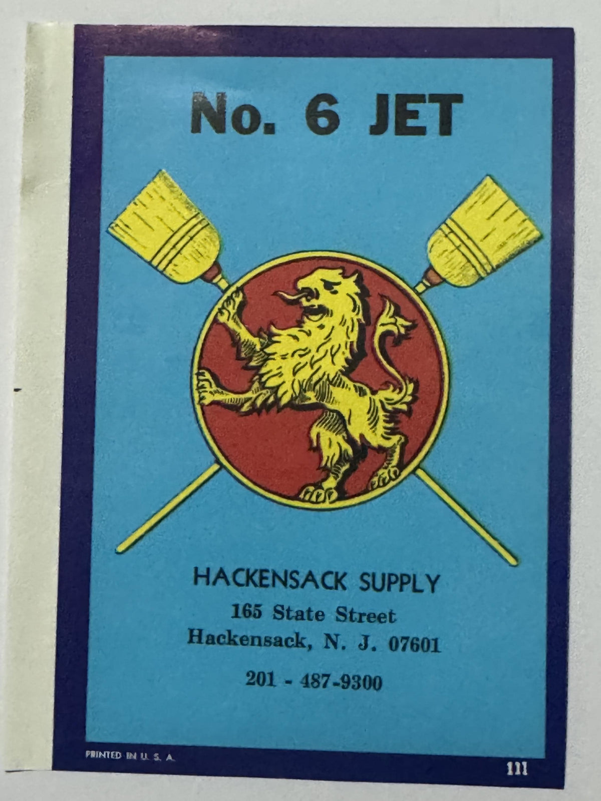 Hackensack Supply No. 6 JET broom label: a yellow rampant lion on a red disc between two crossed yellow brooms, light blue field, purple border, cream margin strip at the left