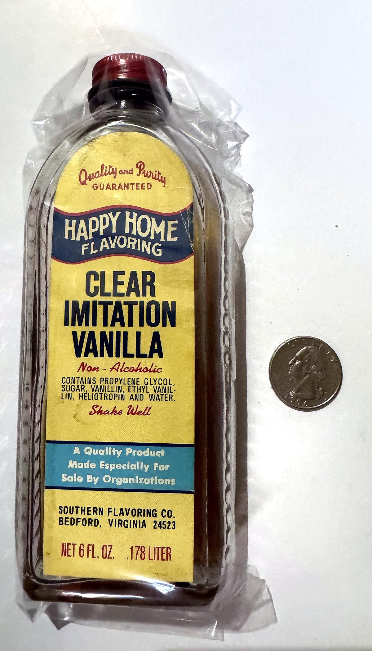 Happy Home vanilla bottle in a clear sleeve beside a quarter for scale
