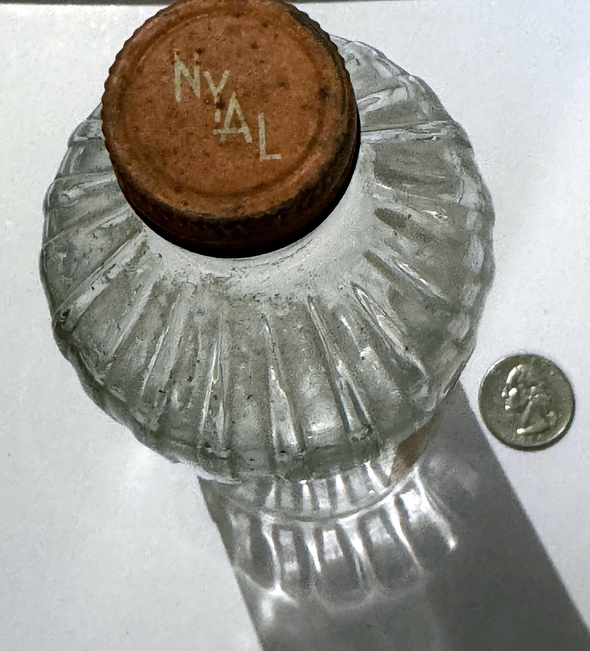 Top of the metal screw cap printed NYAL in stepped letters, above the ribbed glass shoulder