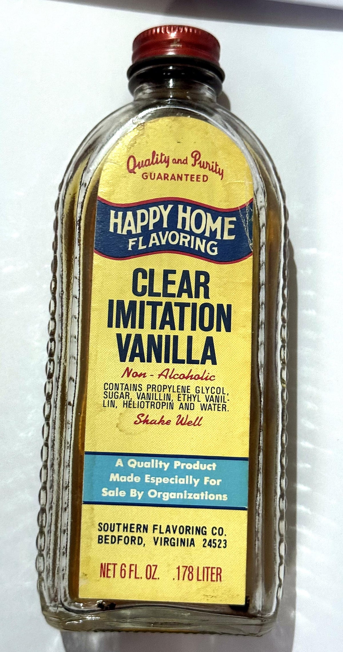 Vintage Happy Home Clear Imitation Vanilla bottle from Southern Flavoring Co. of Bedford, Virginia, with its red Happy Home cap