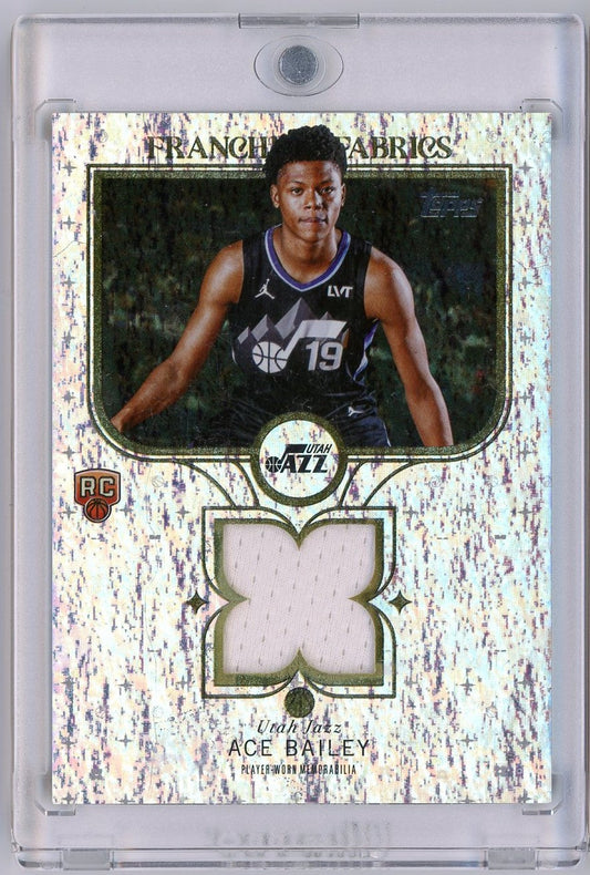 Front of basketball card displaying Ace Bailey in Utah Jazz black jersey number 19, with cream-colored fabric swatch inset and speckled white background.