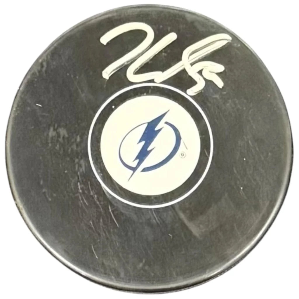 Black hockey puck featuring a white circular tampa bay lightning logo with blue lightning bolt and jake guentzel autographed in white marker