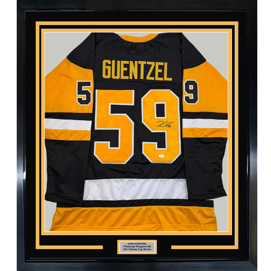 Framed black and gold Pittsburgh Penguins #59 jersey signed by Jake Guentzel, displayed flat against gray backing with yellow border matting.