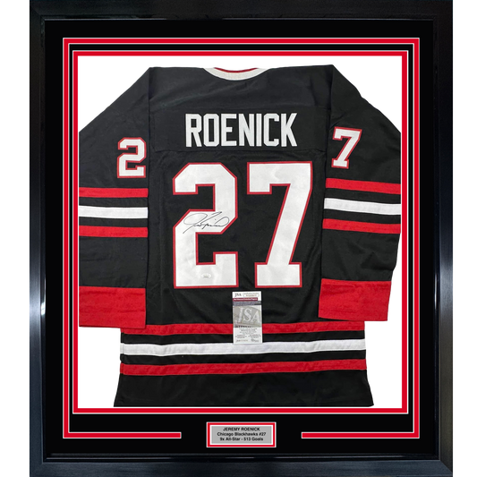 Black Chicago Blackhawks hockey jersey number 27 signed by Jeremy Roenick displayed in red-bordered frame with nameplate.