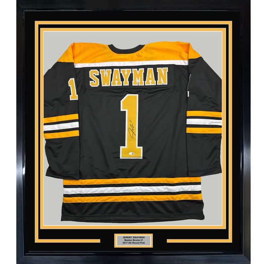 Framed black Boston Bruins hockey jersey number 1 with "Swayman" printed on back, displayed front-facing with gold and white striping, mounted in black frame with nameplate.