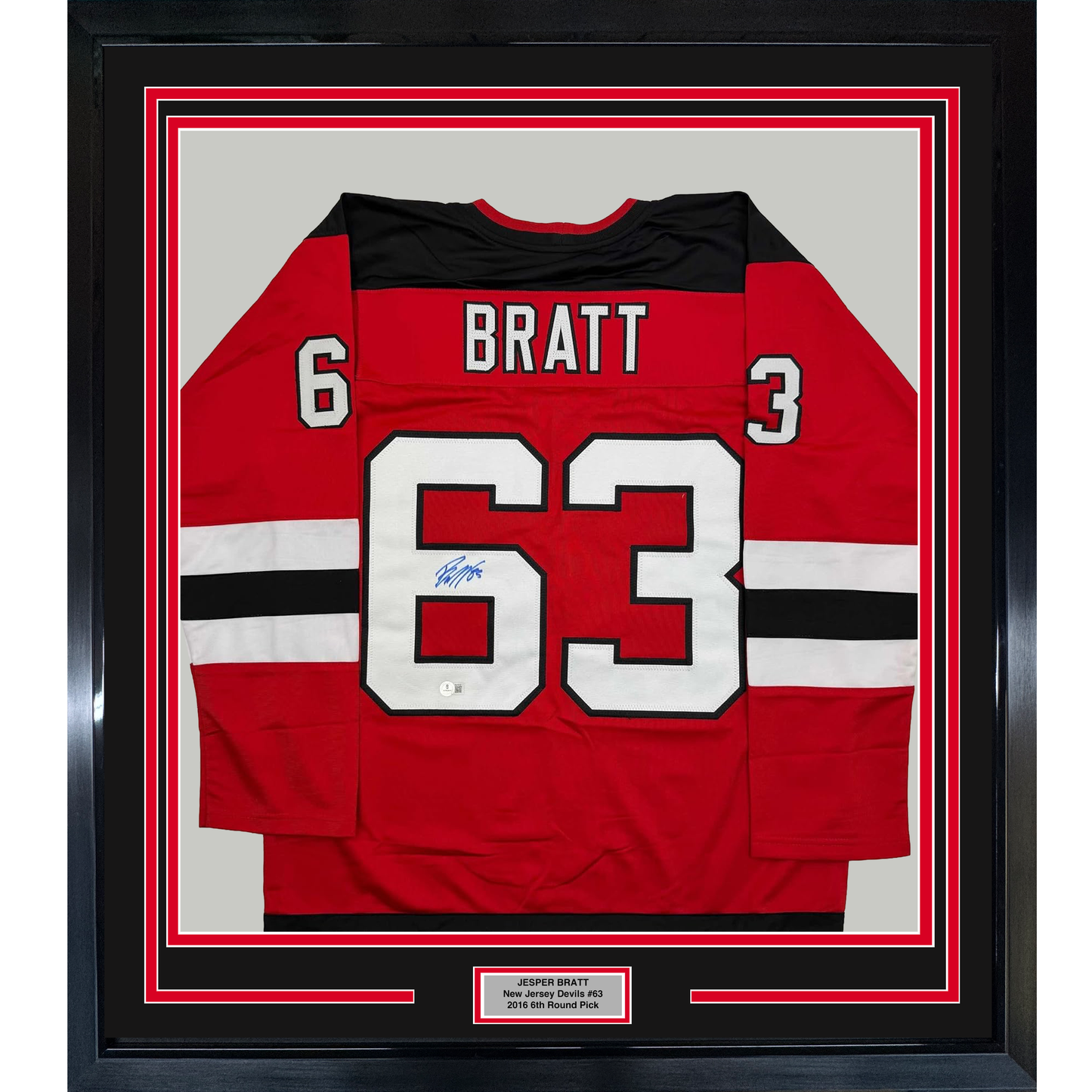 Framed red New Jersey Devils hockey jersey number 63 with "BRATT" nameplate and autograph, displayed flat against white matting with black border frame.