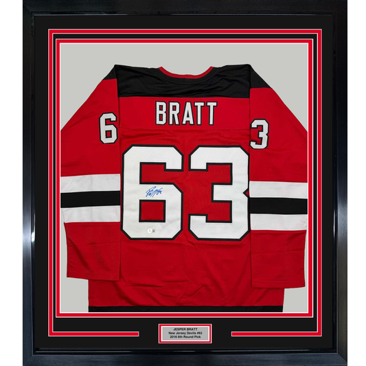 Framed red New Jersey Devils hockey jersey number 63 with "BRATT" nameplate and autograph, displayed flat against white matting with black border frame.