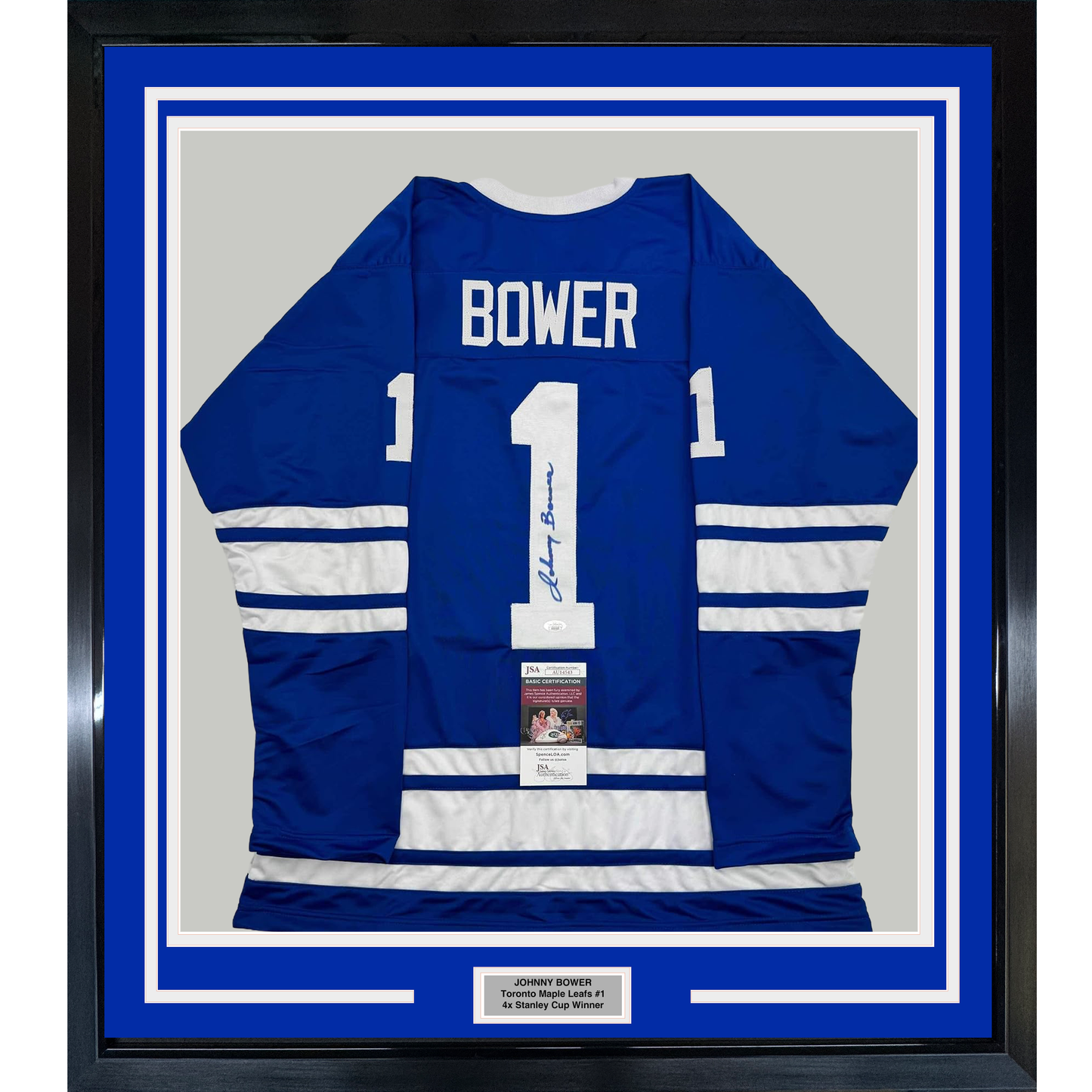 Framed blue and white Toronto Maple Leafs #1 hockey jersey signed by Johnny Bower, displayed flat against gray backing with authentication certificate visible.