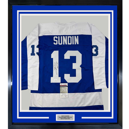 Framed Toronto Maple Leafs blue and white hockey jersey number 13 with "SUNDIN" nameplate and autographed signature, mounted with JSA authentication certificate and nameplate on blue matting.