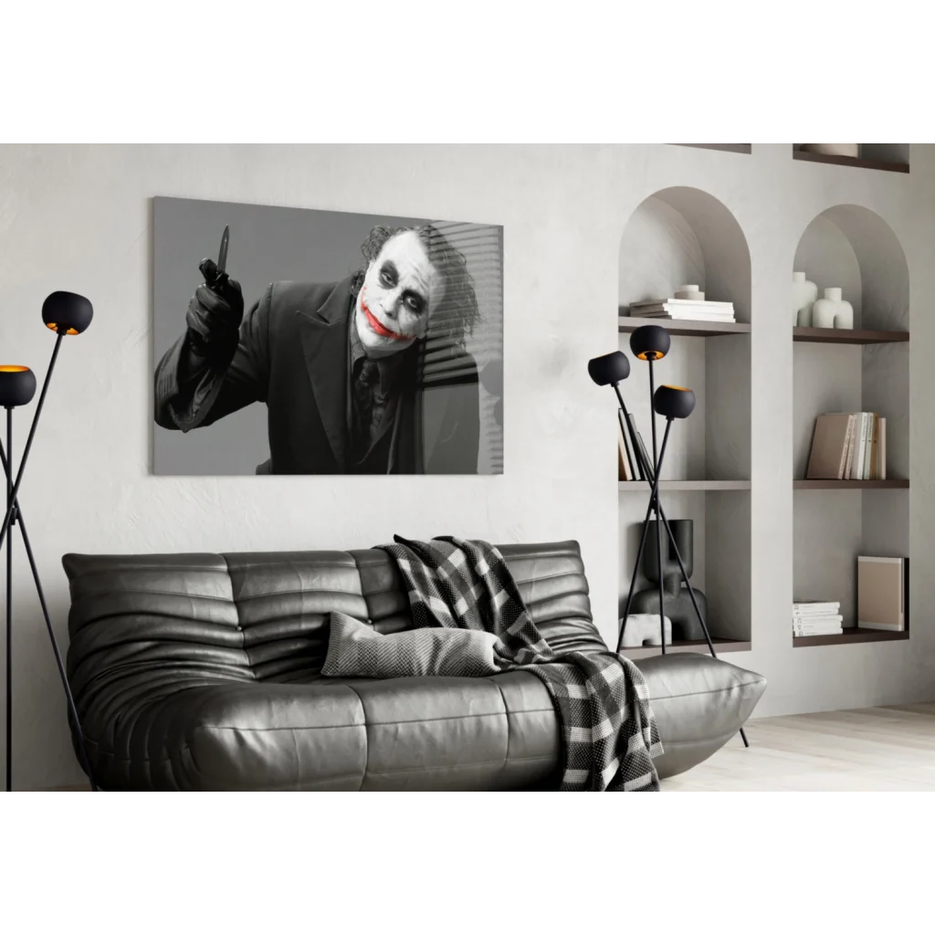 Joker wall art with knife and red lips above black leather sofa