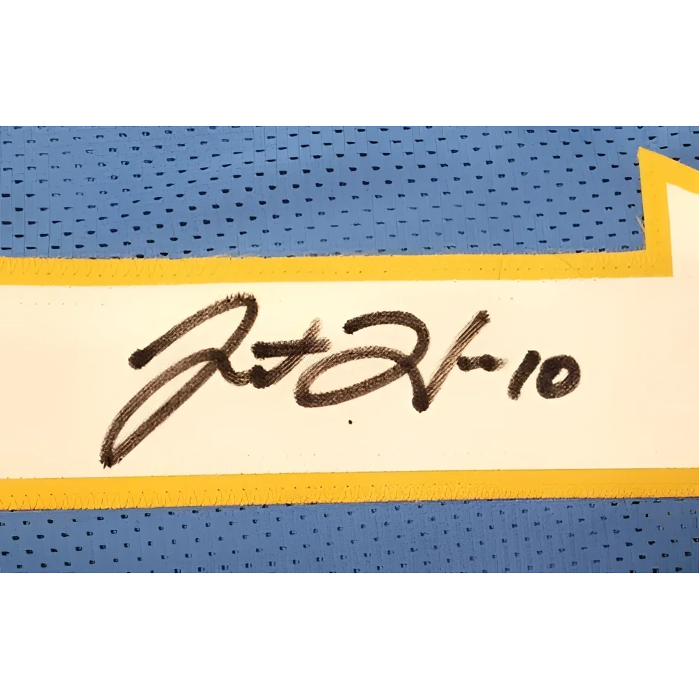 Black ink signature on a white label bordered by yellow on a blue mesh fabric of justin herbert autographed powder blue jersey