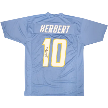 Back of a powder blue mesh football jersey with herbert 10 in white outlined in yellow and justin herbert autographed signature