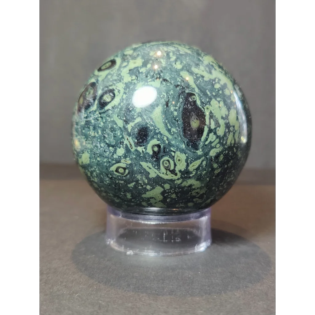 A kambaba crocodile jasper polished sphere sculpture featuring a green and black jasper polished sphere with swirling patterns