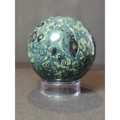 A kambaba crocodile jasper polished sphere sculpture featuring a green and black jasper polished sphere with swirling patterns