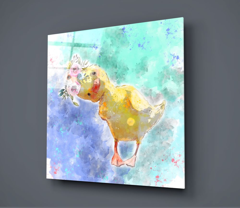 Glass wall art panel displaying a yellow duckling holding pink flowers against a watercolor background in mint green and blue tones, angled view.