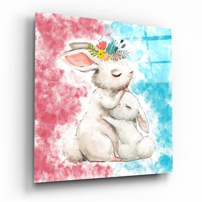 Glass wall art displaying a watercolor illustration of a white mother rabbit holding a small bunny, wearing a floral crown, against pink and blue watercolor backgrounds.