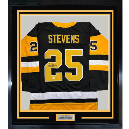 Framed black Pittsburgh Penguins hockey jersey #25 with yellow and white stripes, signed by Kevin Stevens, displayed front-facing with nameplate below.