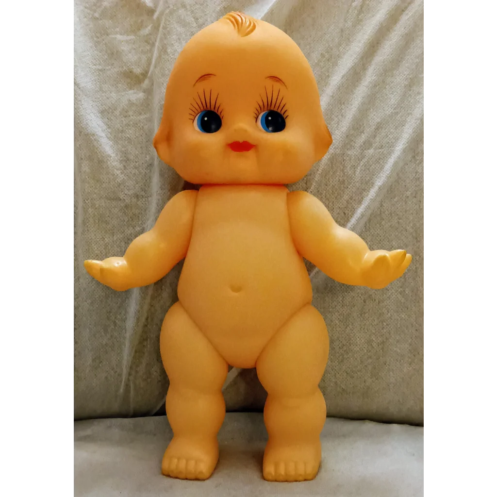 Vintage yellow Kewpie doll with nostalgic charm, red lips, blue eyes, plastic squeaker