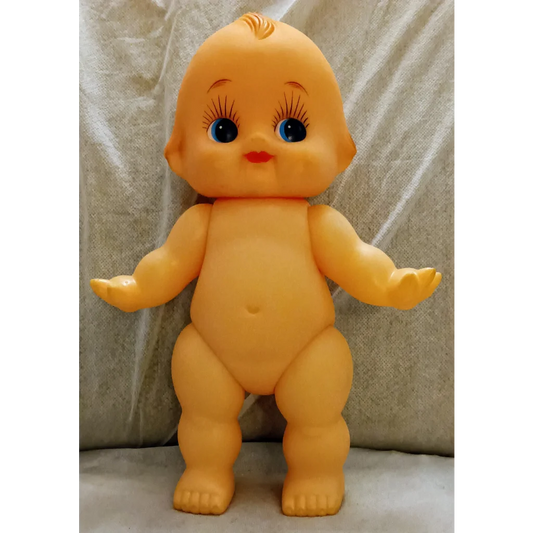 Vintage yellow Kewpie doll with nostalgic charm, red lips, blue eyes, plastic squeaker