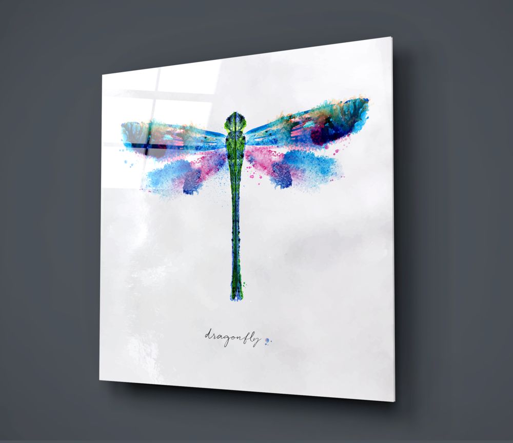 Angled view of glass wall art displaying a watercolor dragonfly with blue, pink, and green hues and "dragonfly" text below, mounted on gray wall.