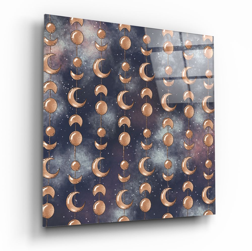 Angled perspective view of glass wall art displaying copper moon phases and circles hanging from strings against a dark starry night sky background.